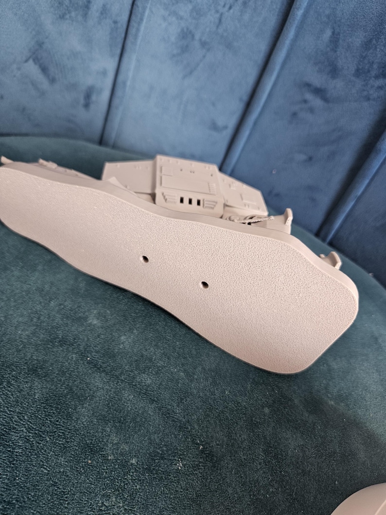 May include: A beige plastic model of a spaceship with a detailed underside. The model has two small holes on the bottom.