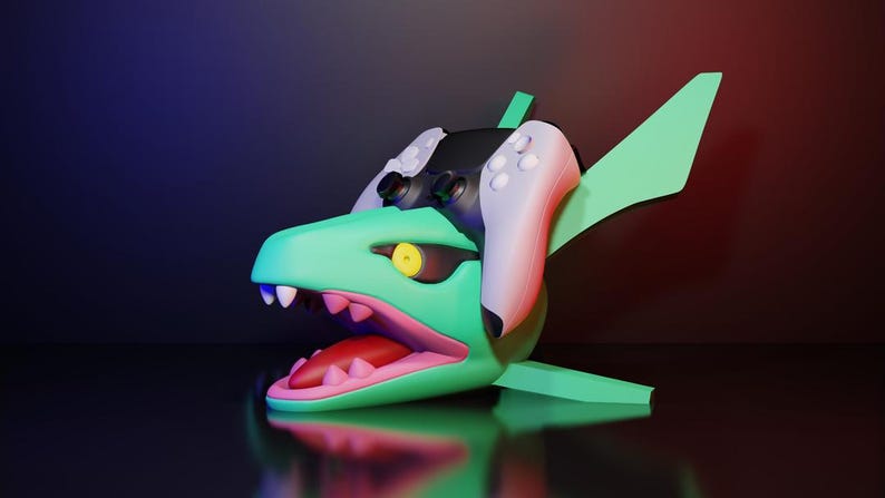May include: A stylized, 3D-rendered sculpture of a shark-like creature with a gaming controller integrated into its design. The sculpture is primarily green with white teeth, a pink mouth, and a yellow eye. The controller is black and white. The background is a gradient of blue and red.