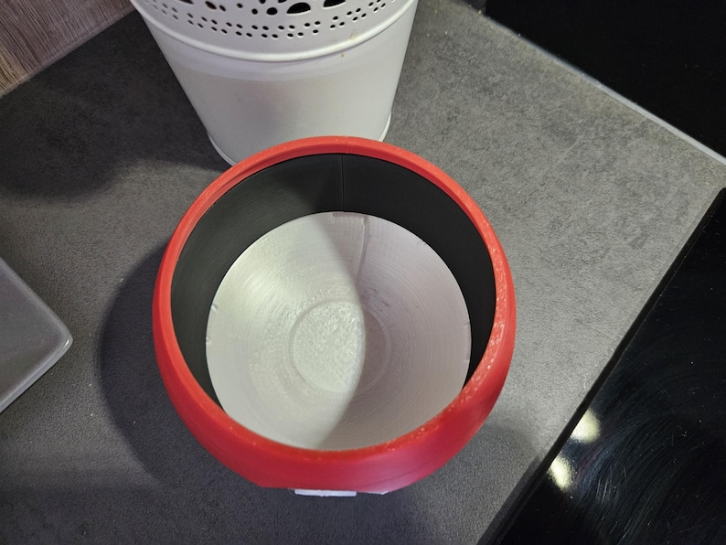 May include: A red ceramic planter with a white interior and a black rim. The planter is empty and ready for a plant.