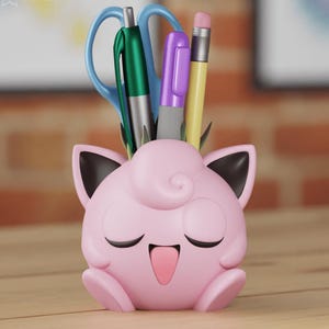 Può includere: Organizzatore da scrivania rosa a forma di personaggio dei cartoni animati con un viso sorridente. L'organizzatore ha un paio di forbici blu, una penna verde, una penna viola e una matita gialla che sporgono dalla parte superiore.