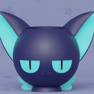 May include: A dark blue ceramic cat-shaped planter with teal ears and eyes. The planter has a cute, cartoon-like expression.