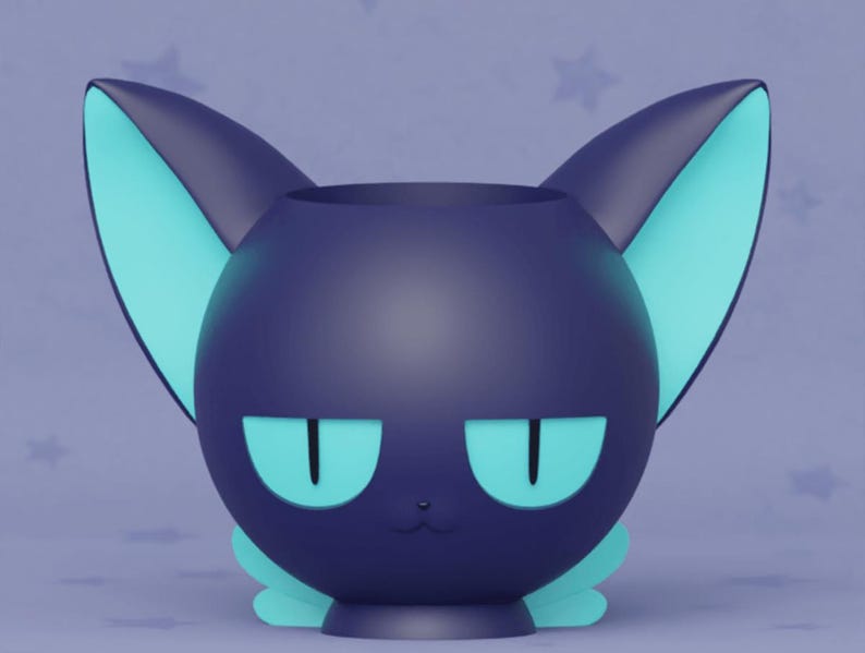 May include: A dark blue ceramic cat-shaped planter with teal ears and eyes. The planter has a cute, cartoon-like expression.