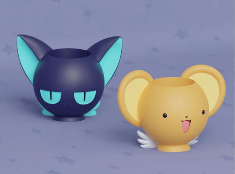 May include: Two ceramic character pencil holders. One is a black cat with teal ears and eyes. The other is a yellow dog with brown ears and eyes and a pink tongue sticking out.