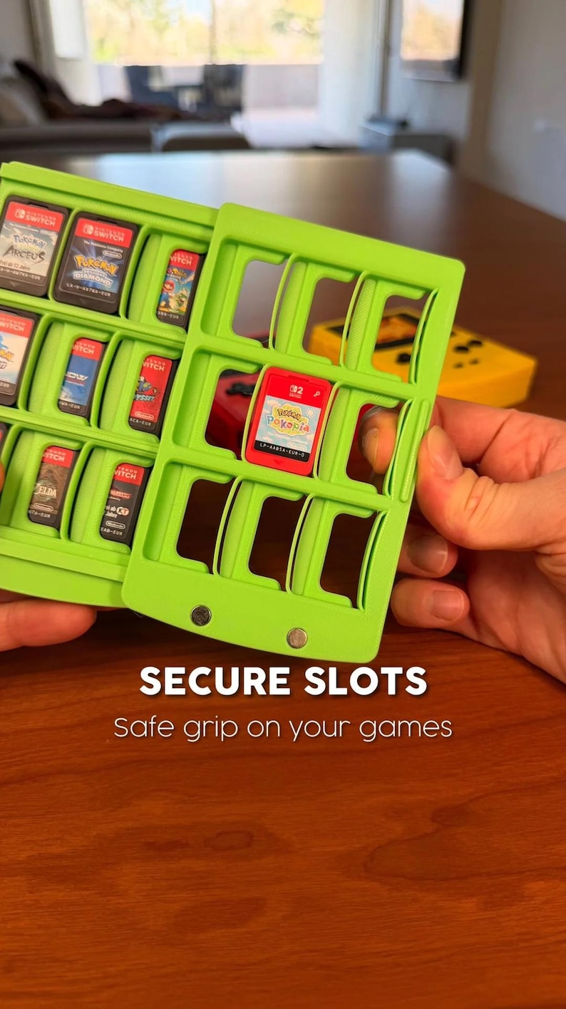 May include: Two bright green game cartridge holders with multiple slots, each holding a game cartridge. The text "SECURE SLOTS" and "Safe grip on your games" is displayed. A yellow game controller is visible in the background.