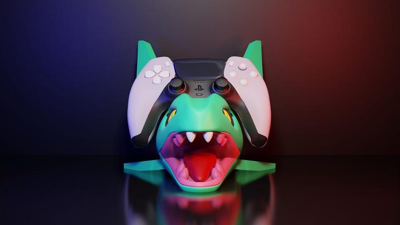 May include: A teal and pink dragon-themed gaming controller stand. The stand features a detailed dragon head design with a wide open mouth and a controller resting on top. The controller has white and black accents.