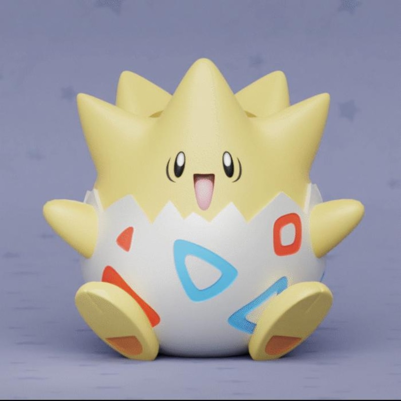 May include: A Togepi figurine, featuring a light yellow spiky head and arms, and a white egg-shaped body with red, blue, and orange accents. The figurine has a smiling face with black eyes and a pink mouth. The background is a light purple.