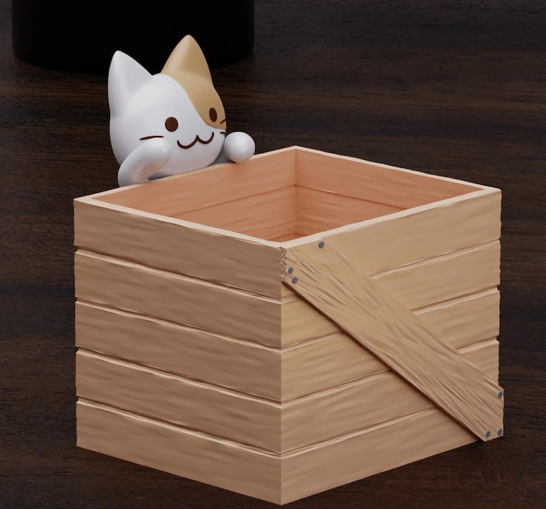 May include: A wooden crate with a cat figurine peeking out of the top. The crate is made of light brown wood with a diagonal brace across the front. The cat is white with brown markings and has a cute expression.