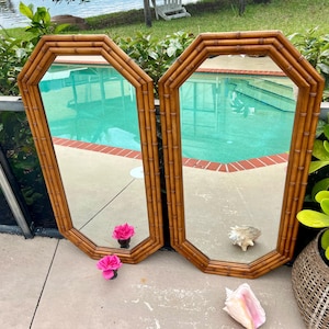 May include: Two matching octagonal wall mirrors featuring light brown bamboo-style frames. The mirrors have a reflective glass surface and a distinct eight-sided shape, showcasing a natural wood-toned finish with visible bamboo segment detailing.