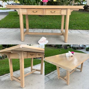 May include: Light wood console table with two drawers featuring woven rattan fronts and brass-toned pulls. The table has a rectangular top and four sturdy legs. A seashell and flowers are on the ground near the table.