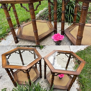 May include: Set of two vintage hexagonal side tables. The tables have a dark brown bamboo-style frame with a woven cane shelf and a glass top. The tables are placed on a stone surface with green grass in the background.