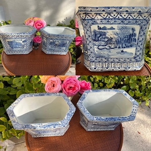 May include: Two blue and white porcelain planters with a floral design. The planters are octagonal in shape and have a raised rim. The planters are sitting on a wooden table.