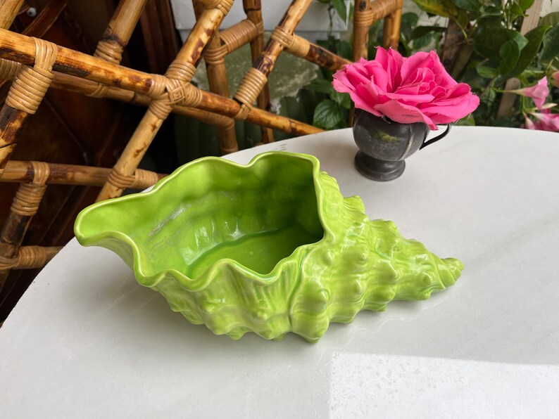May include: A bright green ceramic seashell planter. The planter is shaped like a conch shell and has a textured surface.