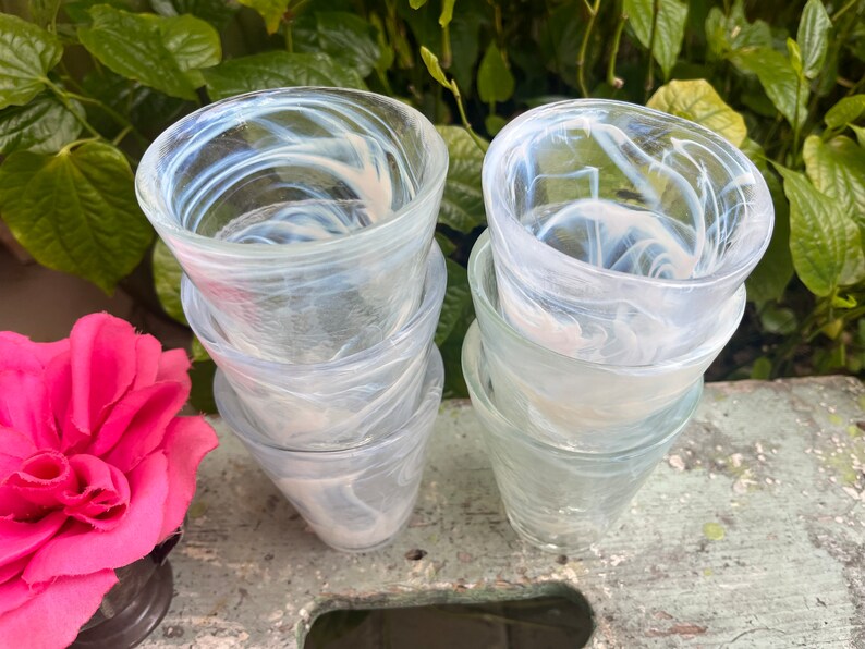 May include: Set of six clear glass tumblers with a swirling white pattern. The glasses are stacked in two groups of three.