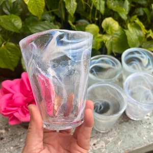 May include: Set of six clear glass tumblers with a white swirl design. The glasses are stacked on a table.