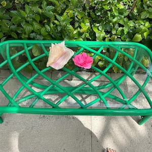 May include: A green bamboo coffee table with a glass top. The table has a woven design and is decorated with a seashell and a pink flower.