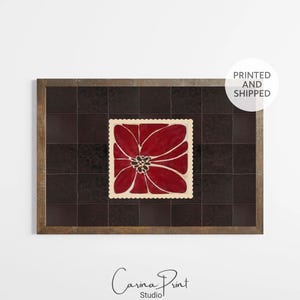 May include: A framed print with a red flower design on a dark brown, tiled background. The flower has a white outline and a black centre. The frame is light brown. The print is from Carina Print Studio.