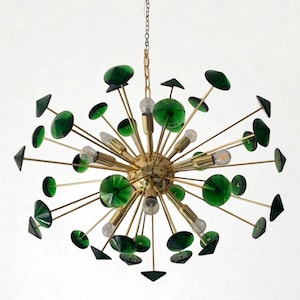May include: A mid-century modern chandelier with a gold-toned metal frame. The fixture features multiple light bulbs and is adorned with green glass accents in various shapes, including discs and triangles. The chandelier hangs from a chain.