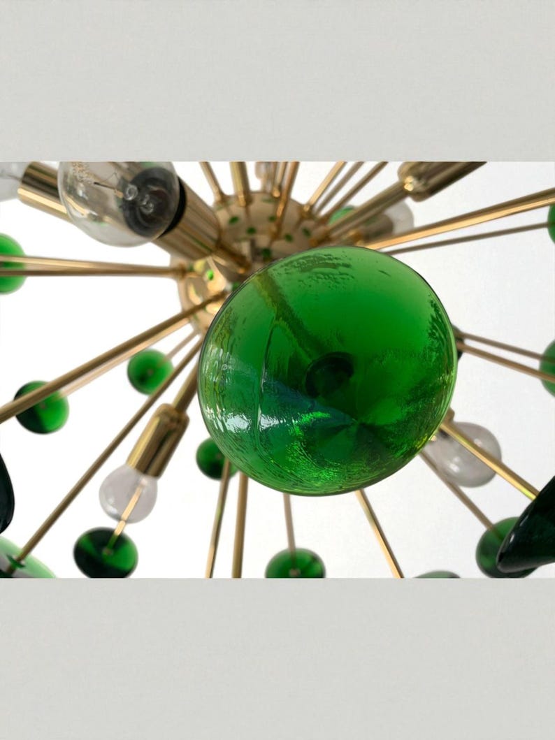 May include: A mid-century modern chandelier with a gold-tone metal frame. The fixture features multiple arms with green glass globes and clear light bulbs. The design is reminiscent of atomic age decor.