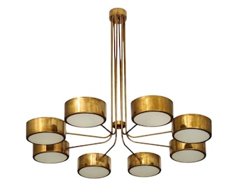 May include: A gold-toned chandelier with eight circular light fixtures. Each fixture has a white interior and a gold-colored exterior. The chandelier has a central stem with multiple arms extending to hold the lights.