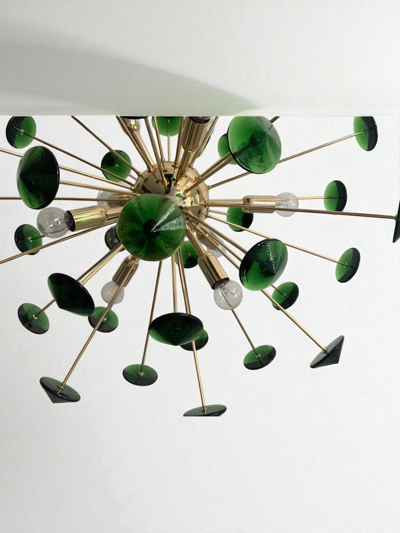 May include: A mid-century modern chandelier with a brass finish and dark green glass accents. The light fixture features multiple arms extending from a central sphere, each holding a green glass disc or sphere. Clear light bulbs are also visible.