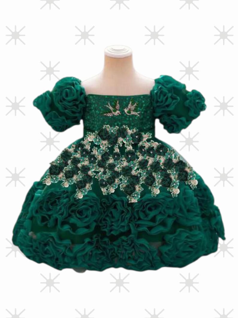 May include: A green dress with a square neckline and short, puffy sleeves. The bodice is embellished with sequins and two bird designs. The skirt is adorned with layers of ruffled fabric, and the waist is decorated with floral accents. A formal dress for a special occasion.