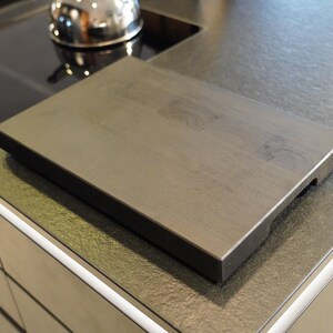 May include: A dark gray rectangular cutting board with a slightly textured surface. The board is made of wood and has a beveled edge.
