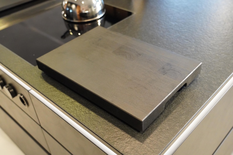 May include: A dark gray rectangular cutting board with a slightly textured surface. The board is made of wood and has a beveled edge.