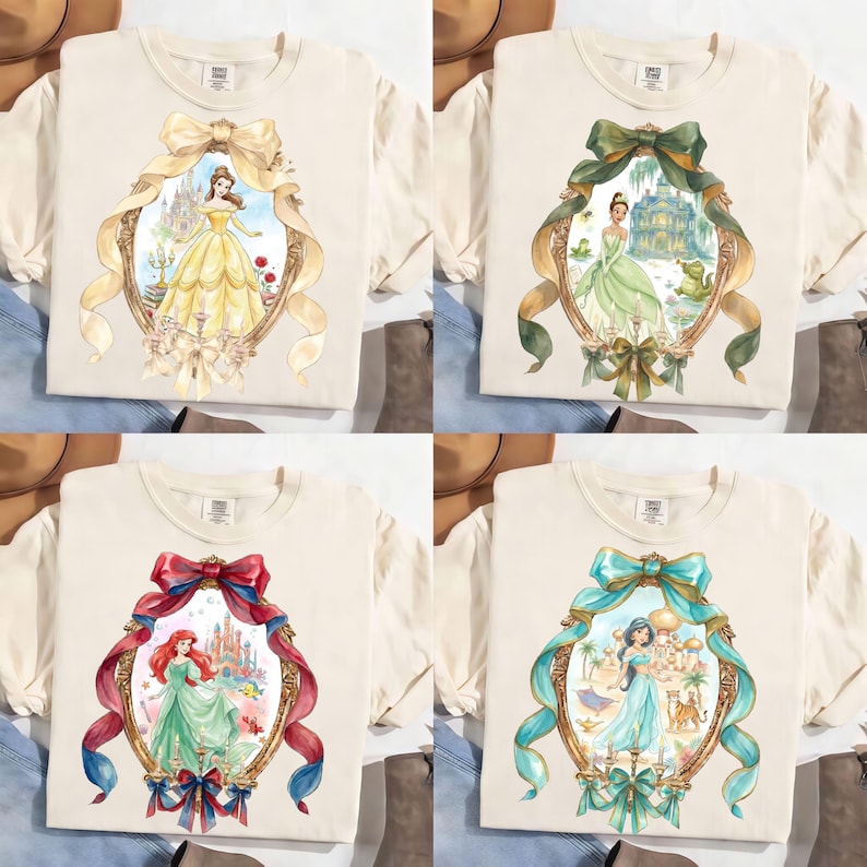 Puede incluir: Cuatro camisetas color crema con diferentes dise&ntilde;os de princesas. Cada camiseta presenta una ilustraci&oacute;n en acuarela enmarcada de una princesa, incluyendo a Bella, Tiana, Ariel y Jasmine. Los marcos est&aacute;n adornados con lazos y cintas.