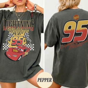 以下が含まれることがあります： 黒い持ち手と「But First, Coffee」の文字が黒い手書き風フォントで書かれた白いセラミックマグ。マグカップは白い表面に置かれています。