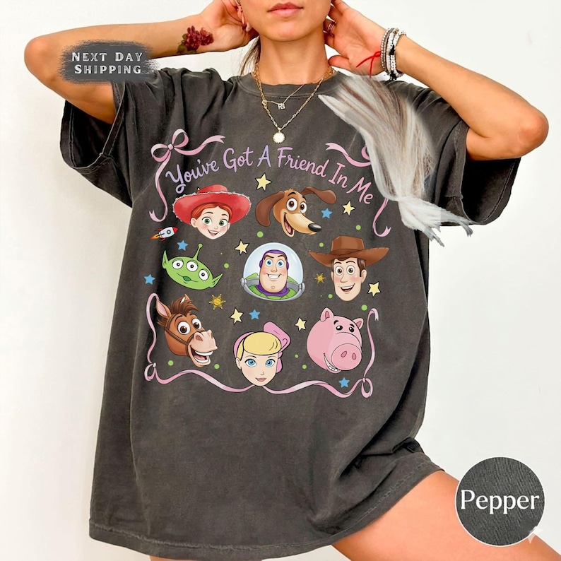 Puede incluir: Camiseta gris oscuro con un gr&aacute;fico colorido de personajes de la pel&iacute;cula "Toy Story". El dise&ntilde;o incluye la frase "You've Got A Friend In Me" en escritura rosa. La camiseta es de corte holgado.