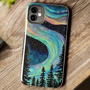 May include: A protective phone case featuring a vibrant, iridescent depiction of the aurora borealis swirling across a dark, starry night sky above a silhouette of black pine trees. The design includes shimmering waves of blue, green, and purple.
