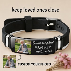 Könnte beinhalten: Schwarzes Silikonarmband mit einer rechteckigen Metallplatte mit einem Foto und dem Text "Forever in my heart Robert 1942-2025." Der Text "keep loved ones close" und "CUSTOM YOUR PHOTO" sind ebenfalls sichtbar.