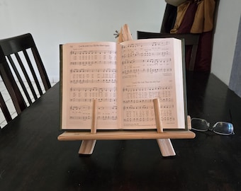 A book easel is a stand or support designed to hold a book upright and open—perfect for reading, displaying without using your hands.