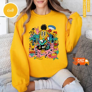 トロピカルな漫画風パーティーシャツ、楽しいアナナスの頭のグラフィックTシャツ、シュールな夏のビーチアート、カラフルなフェスティバルスタイルのデザイン、友人へのギフト