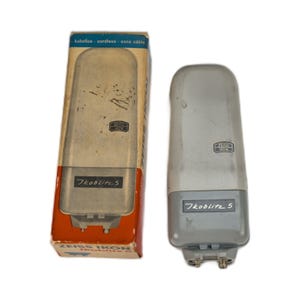 May include: Vintage Zeiss Ikon 7koblit5 flash unit and its original box. The flash is gray and white with the Zeiss Ikon logo. The box is tan, red, and blue with the flash's image and text. The box reads "kabellos - cordless - sans cable."