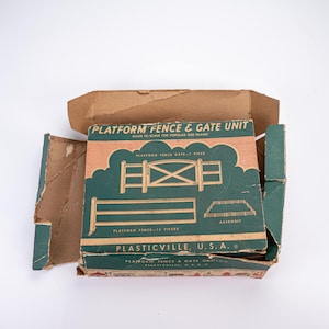 May include: A vintage cardboard box for a Plasticville U.S.A. Platform Fence & Gate Unit. The box is green and orange with illustrations of a fence and gate, featuring the text Platform Fence & Gate Unit, Made to scale for popular size trains.