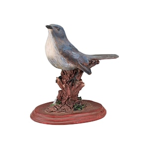 Figura coleccionable de resina pintada a mano de un pájaro azul sobre una base de tronco de árbol.
