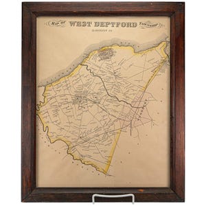 May include: Framed vintage map of West Deptford Township, Gloucester Co. The map features detailed lines and text, with yellow and brown colouring. The map is encased in a dark brown wooden frame and displayed on a white stand.