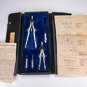 Può includere: Un set di compassi da disegno VEMCO vintage in una custodia nera con rivestimento in velluto blu. Il set include due compassi in metallo argentato, un manico nero e due piccoli accessori. Sono inclusi un foglio di istruzioni e un diagramma.