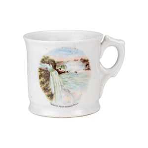 May include: White ceramic mug with a handle, featuring a colorful illustration of Niagara Falls. The image includes the text "PROSPECT POINT NIAGARA FALLS." The mug has a slightly flared base and a decorative handle.