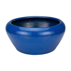 Puede incluir: Un cuenco pequeño y redondo de cerámica azul con una abertura ancha y una superficie ligeramente texturizada. El cuenco tiene un color azul intenso y un diseño simple y elegante, adecuado para diversos usos.