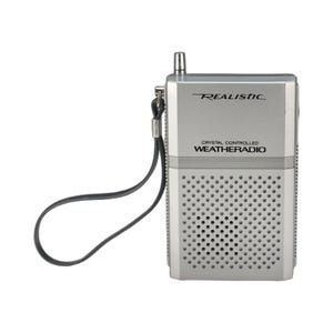 Peut inclure: Une radio météo Realistic argentée avec une sangle noire. La radio est dotée d'une petite antenne et d'une grille de haut-parleur. Le texte "REALISTIC" et "CRYSTAL CONTROLLED WEATHERADIO" est imprimé sur le devant.