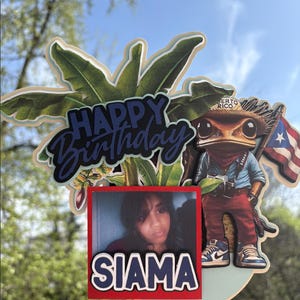 May include: A birthday cake topper featuring a cartoon frog wearing a hat that says "Puerto Rico" and holding a Puerto Rican flag. The topper also includes a palm tree, the words "Happy Birthday", and a photo of a person with the name "Siam" written below.
