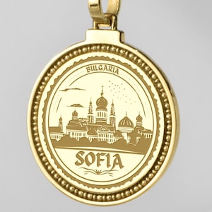 Può includere: Collana con pendente dorato con un'incisione dettagliata di Sofia, Bulgaria, e il nome della città. Il pendente è appeso a una catena a corda dorata abbinata. Un accessorio elegante.