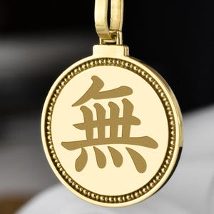 May include: Gold-toned pendant necklace featuring a circular pendant with an engraved Japanese character. The pendant is suspended from a rope chain. The necklace is a jewelry item.