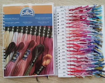 Puede incluir: Un gráfico y guía de colores de hilo de bordar DMC encuadernado en espiral. El lado izquierdo muestra madejas de hilo en tonos rosas, rojos y marrones. El lado derecho muestra muestras de color con los números DMC. Texto en inglés y francés.
