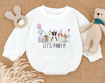 May include: White baby onesie with a graphic of several cartoon dogs wearing party hats and holding balloons. The text "LET'S PAWTY!" is printed below the dogs. A wooden bunny-shaped teether and a stuffed teddy bear are in the background.