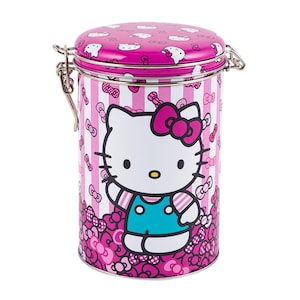 May include: A cylindrical metal container with a hinged lid, featuring a pink and white striped pattern. The container is adorned with images of Hello Kitty and bows. The lid and base are a solid pink color, and the container has a silver clasp.