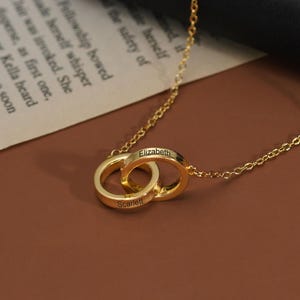 Könnte beinhalten: Ein Set aus drei Keramikbechern mit gesprenkelter, matter Oberfläche. Die Becher sind in Creme-, Hellgrau- und Dunkelgrautönen gehalten. Jeder Becher hat ein schlichtes, minimalistisches Design und einen abgerundeten Henkel.