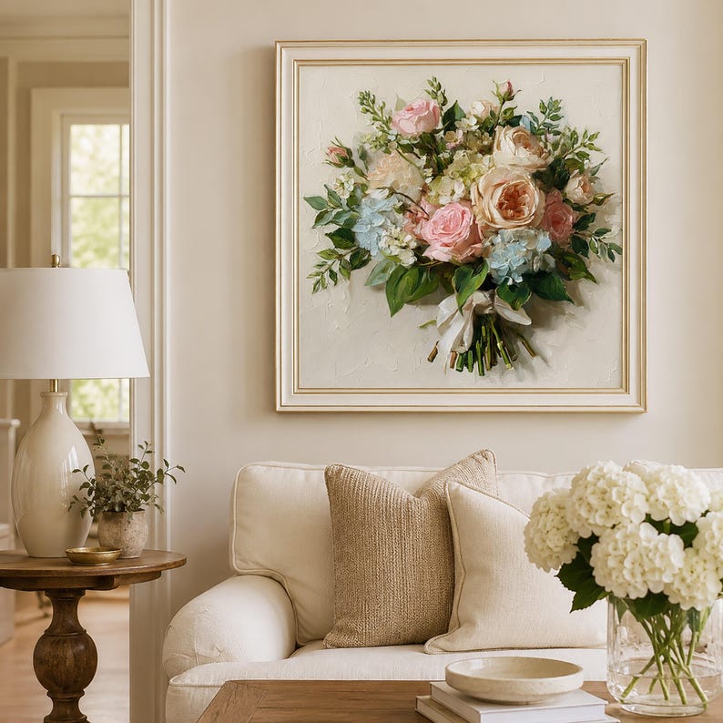 May include: A square framed wall art piece featuring an oil painting of a floral bouquet. The arrangement includes pink and peach roses, light blue hydrangeas, and green foliage, tied with a white ribbon against a textured off-white background.